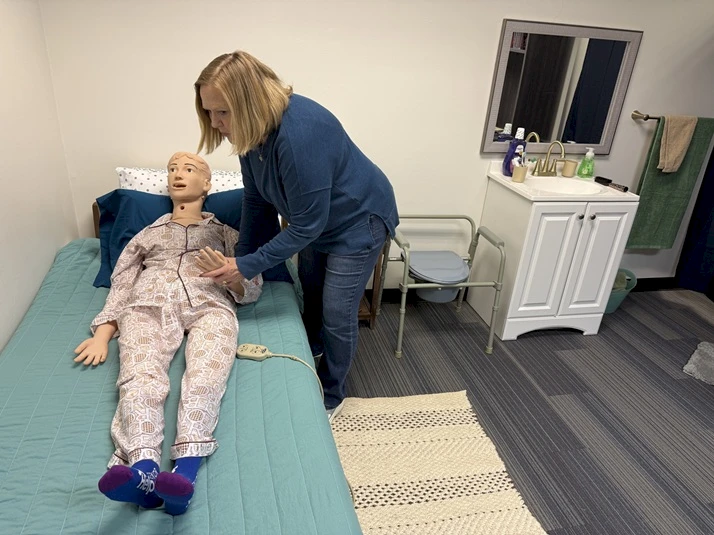Senior Helpers Portland West Owner Denise Graham uses “Darla” the Manikin to demonstrate how to help position a senior in bed. Caregivers are taught how to safely help seniors with activities of daily living.